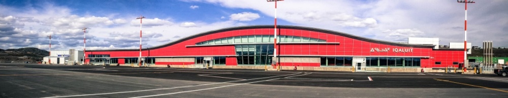Exterior of Iqaluit International Airport, a modern looking building with bright red exterior and rounded roof.