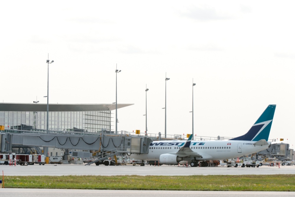 A plane sits at the gate of an airport, surrounded by airfield equipment.
