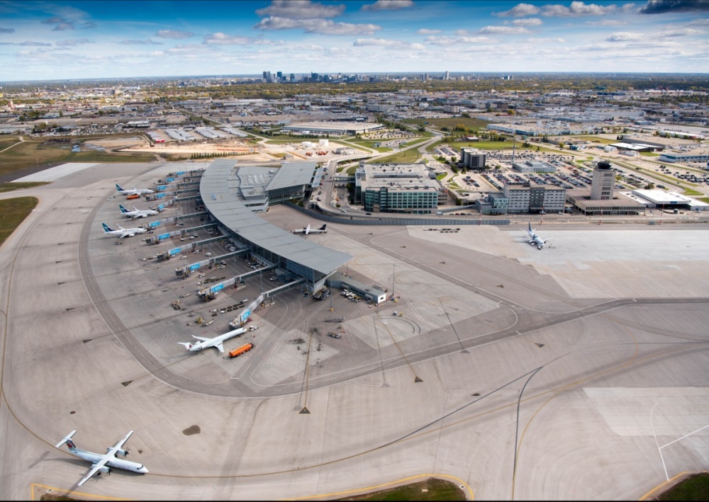Aerial view of Winnipeg Richardson International Airport with the city scape in the background. Taken from the airfield, where planes are sitting at gates.
