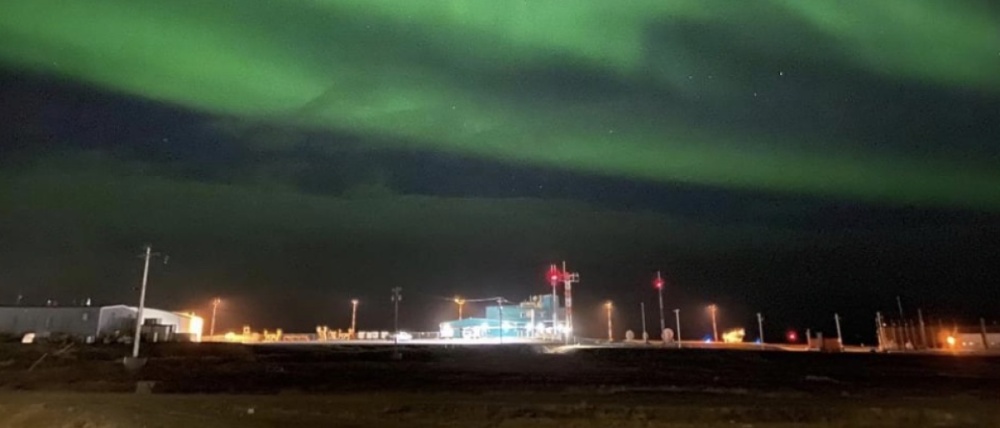 Bright green northern lights over a remote northern airport.