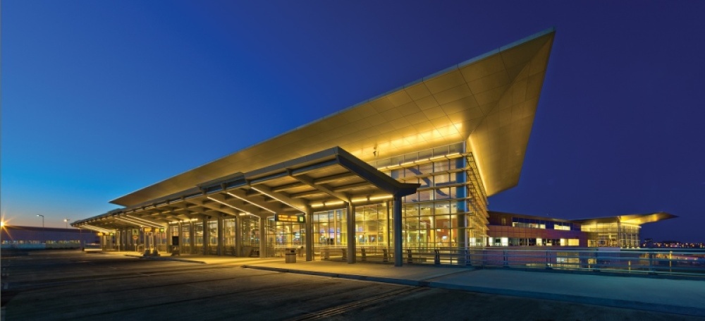 A closeup of the terminal building at night, glowing in ambient light with dark blue sky in the background.