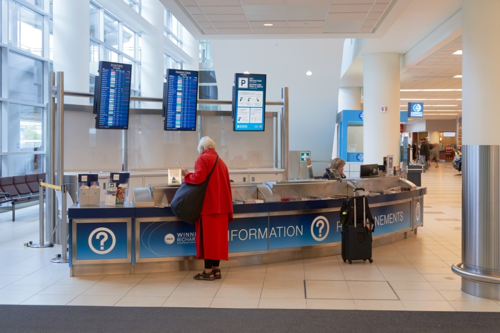A woman stands at the information desk at the airport.