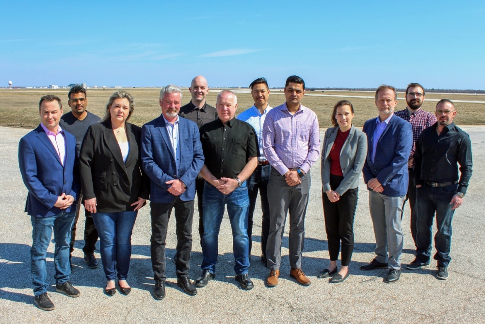 Twelve WASCO employees stand for a group photo on the airfield in Winnipeg.