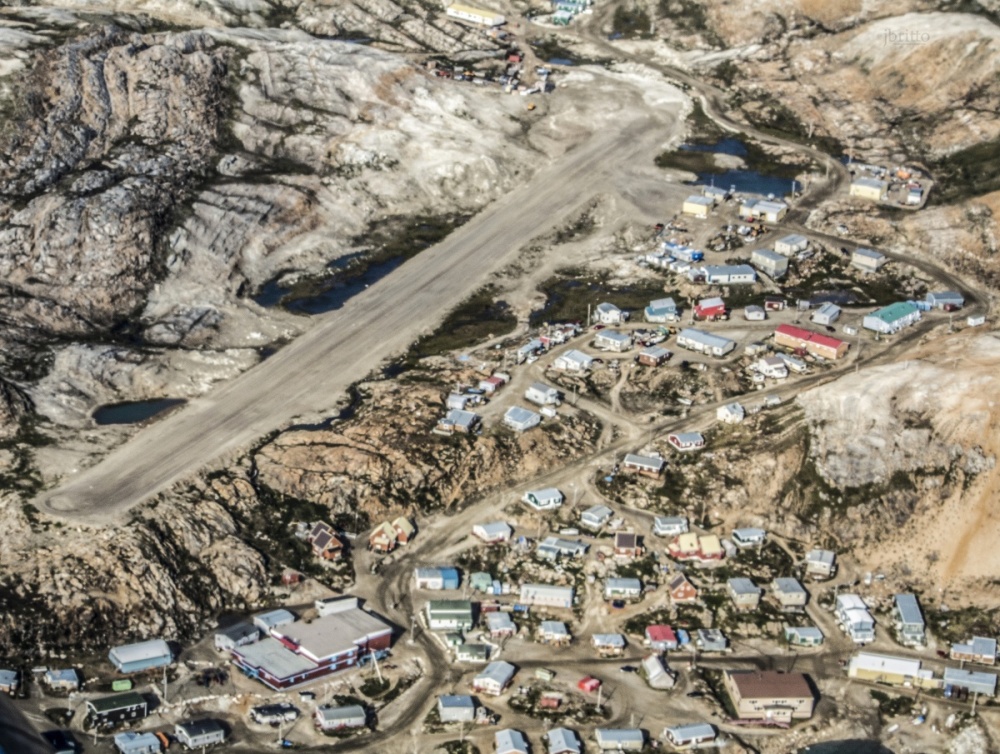 Aerial photo of a runway beside a remote northern airport community.